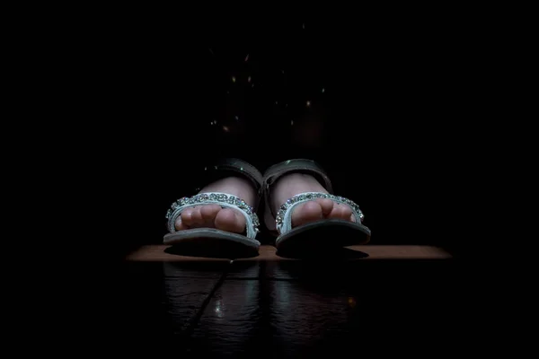 Feet girl with sandals and light reflecting in the crystal of the sandals