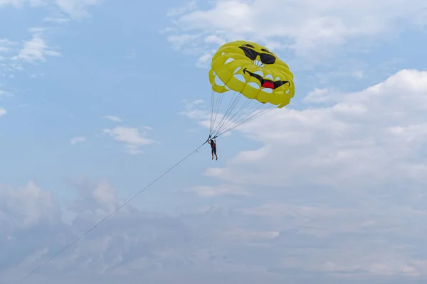 Parasailing, única pessoa pendurada sob paraquedas contra o céu azul nublado — Fotografia de Stock