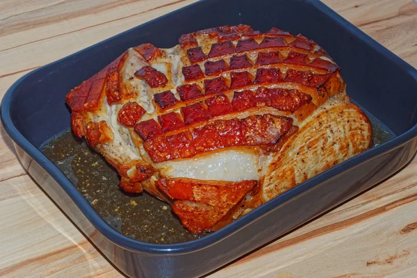 Schweinebraten mit Knistern in der Auflaufform auf Holzgrund lizenzfreie Stockbilder