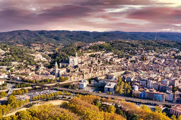 İspanya 'nın Girona şehrinin havadan görünüşü. Günbatımı gökyüzü, evler, sokaklar, şehir parkı ve yollar.