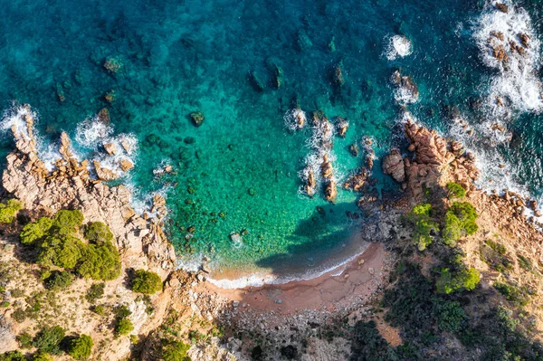 Deniz havası manzaralı. Üst manzara, doğa arka planı. Güneşli bir günde, kayalık dağları ve berrak suları olan gök mavisi deniz plajı. Uçan İHA. Tropik ağaçlar.