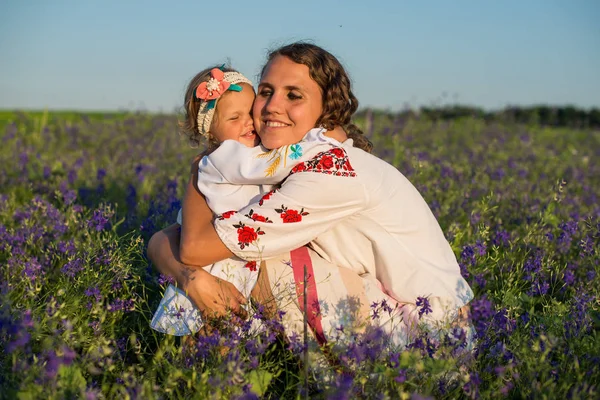 Smiling mother and little daughter on nature in a field of poppies, girl is holding flowers. Happy people outdoors — Stock Photo, Image