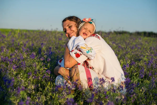 Mère et petite fille souriantes sur la nature dans un champ de coquelicots, la fille tient des fleurs. Des gens heureux à l'extérieur — Photo