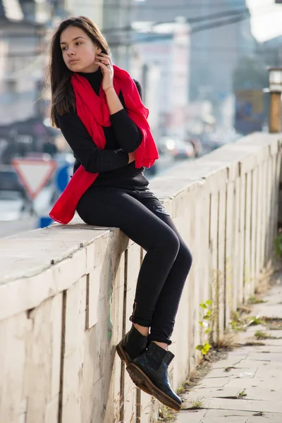 Young girl dressed in casual chinos, black sneakers and walking on a street with wall in background. — Stock Photo, Image