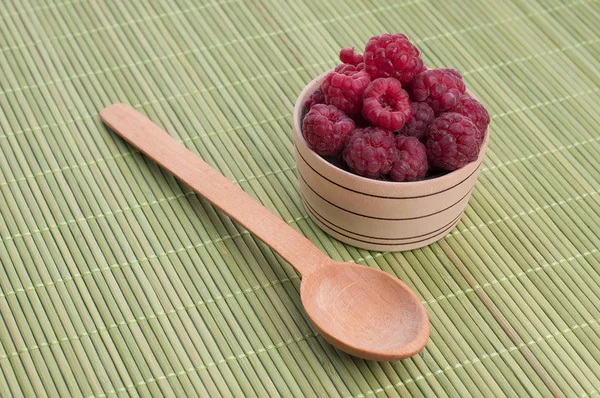 Foto van verse frambozen in een kom met munt op houten tafel — Stockfoto