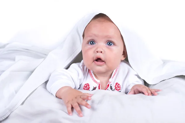 Chica feliz escondida en la cama bajo una manta blanca o cobertor. Chica en la cama. Niño en la cama. aislado sobre fondo blanco —  Fotos de Stock