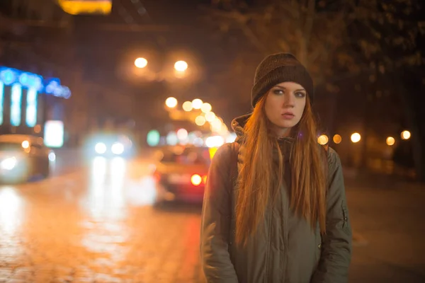 Young beautiful girl catches a taxi in the city street at night — Stock Photo, Image