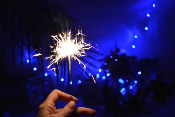 Bengal light in hand blue Christmas light and New Year dark holiday background