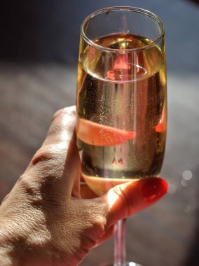 Champagne glass in the female hand in the sunligh