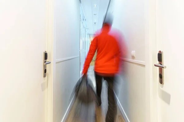 Turista borroso que llega al hotel a lo largo del pasillo, larga exposición —  Fotos de Stock