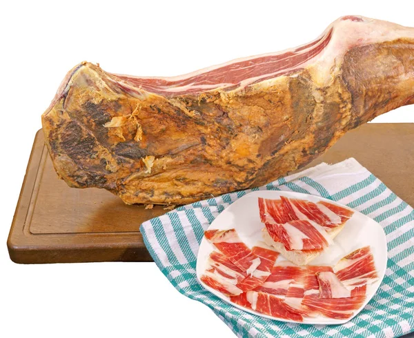 Closeup of serrano ham leg with plate and tablecloth — Stock Photo, Image