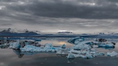 Mavi icebergs hızlandırılmış gece yarısı güneşinin altında yüzen