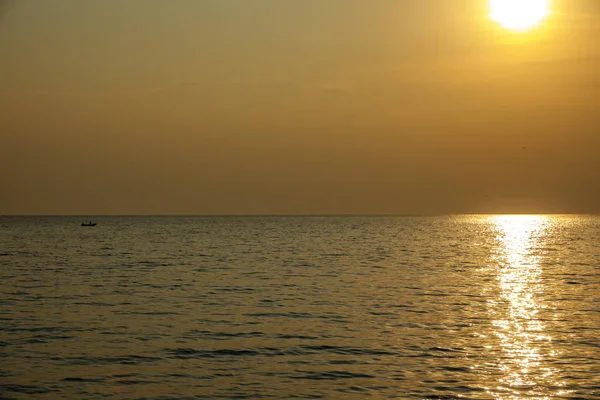 Small boat arriving to coast at sunset — Stock Photo, Image