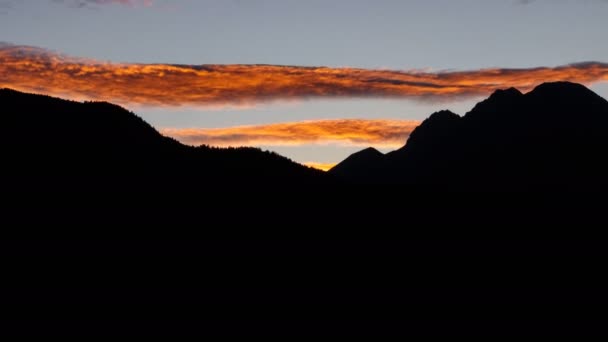 Обертається помаранчевий довгий проміжок часу хмари над чорним профілем гір — стокове відео
