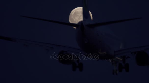 Atterrissage de jet la nuit contre pleine lune, vue du bas 