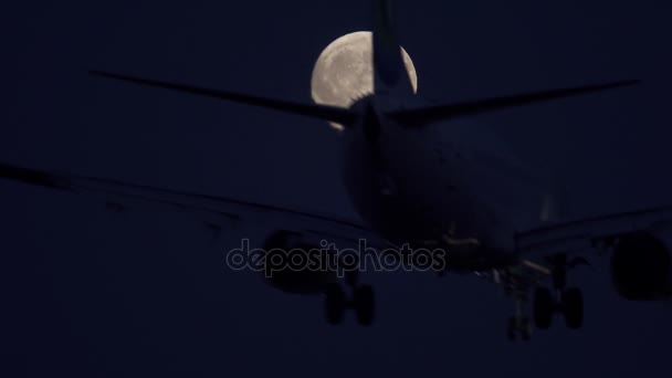 Jet aterrizaje en la noche contra la luna llena, vista inferior — Vídeos de Stock