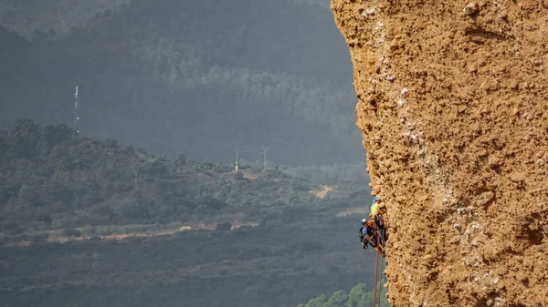Grup tarafından bir uçurum asılı bulanık erkek dağcı — Stok fotoğraf