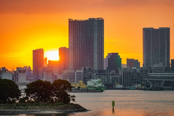 Sunset over office buildings in Tokyo with water reflection — Stock Photo, Image