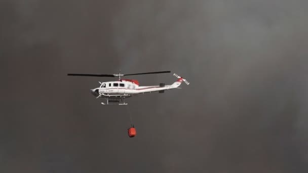 Helicóptero con tanque de agua contra el humo de fuego enorme — Vídeo de stock