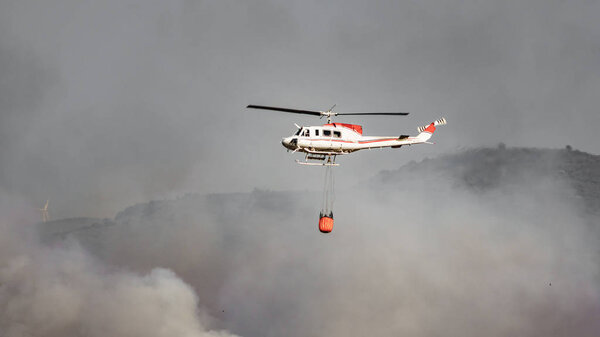 Fire helicopter with water tank against smoke