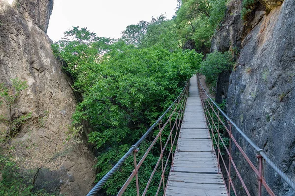 Puente colgante de hierro y madera en cañón entre rocas —  Fotos de Stock
