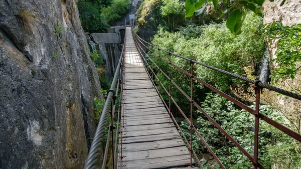 Puente colgante de hierro y madera en cañón entre rocas verticales —  Fotos de Stock