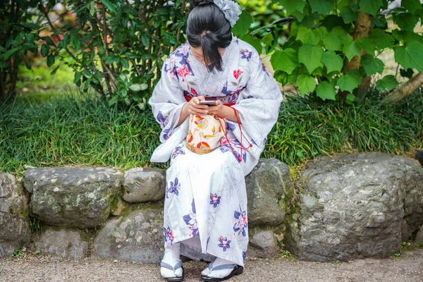 KYOTO, JAPÓN - 8 DE JUNIO DE 2015: Una japonesa no identificada juega con un teléfono móvil vestido con ropa tradicional en Kyoto, Japón — Foto de Stock