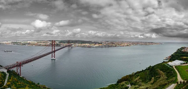 Ovanifrån av 25 de Abril Bridge och Lissabon mot svart himmel — Stockfoto