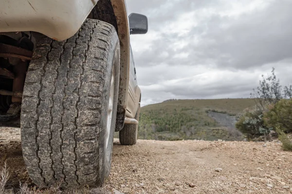 Big 4x4 car wheel stands on backdrop of mountain — Stock Photo, Image