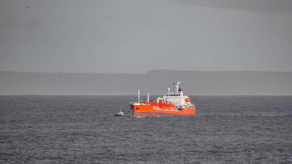 Большая лодка возле серых берегов океана
