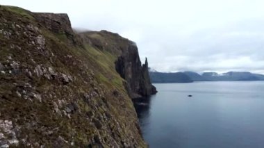 Kamera geriye doğru kayıyor Trollkonufingur, Witchs Finger, Fjord bulutların altında Faroe Adaları