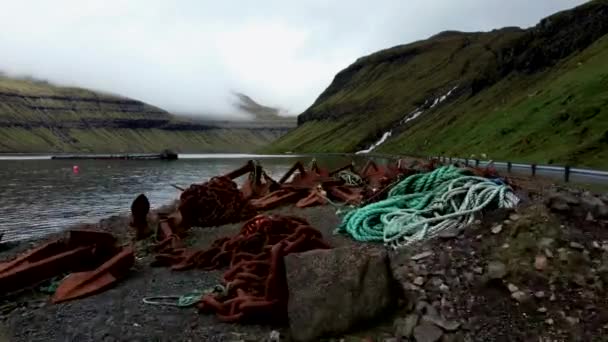 Flying over old rusty anchors in the shore — Stockvideo