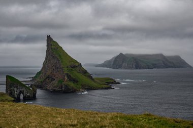 Faroe Adaları 'ndaki bulutlu gökyüzü altında Drangarnir kapısı, Tindholmur ve Mykines