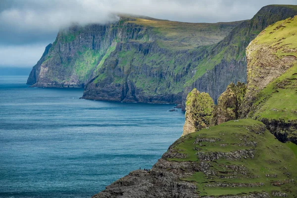Steep coastline of Faroe Islands with tourists — Stock Photo, Image