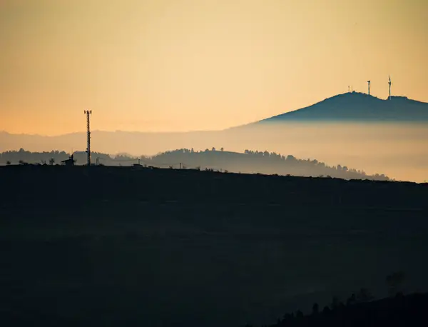 Torre de comunicación retroiluminada al atardecer sobre la montaña —  Fotos de Stock