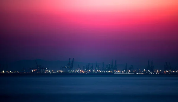 Roze lucht boven de commerciële steiger met kranen — Stockfoto