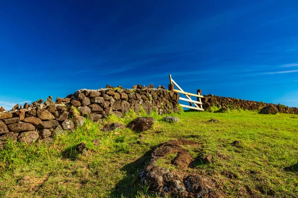 Valla de piedra con puerta de madera bajo cielo azul —  Fotos de Stock