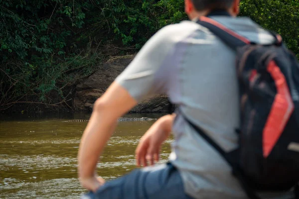 Vue arrière d'un touriste au bord d'une rivière regardant un crocodile — Photo