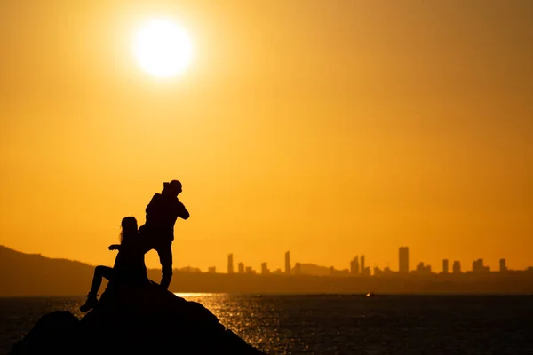 Couple taking social photos at sunset over city skyline — Stock Photo, Image