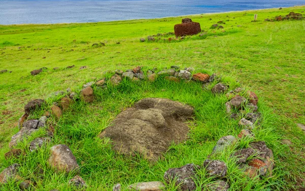 Moai pohřben na zemi obklopený kameny — Stock fotografie