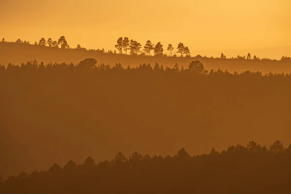 Solnedgång med orange himmel och många skiktade kullar — Stockfoto