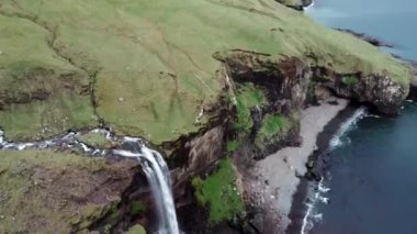 Kamera Faroe Adaları 'ndaki şelaleye doğru eğiliyor.