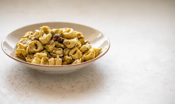 Tortellini al pesto над пунктирной плитой крупным планом — стоковое фото