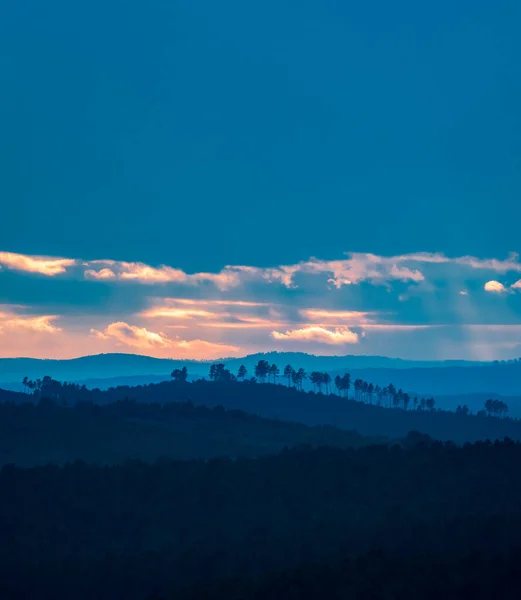 Diferentes capas de colinas al atardecer con cielo azul nublado —  Fotos de Stock