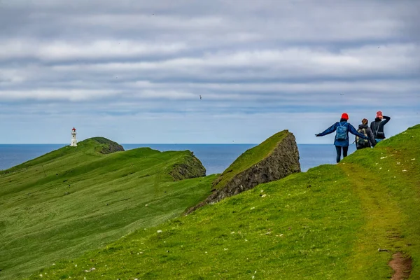 Unrecognizable people hiking to Mykines lighthouse in Faroe islands — Stock Photo, Image