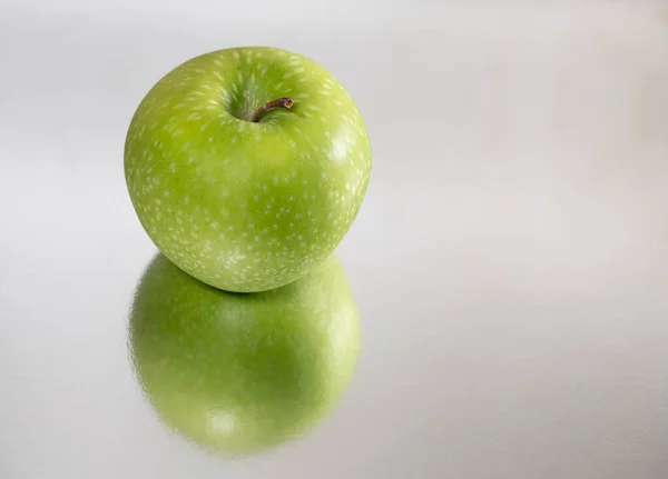 Bright green apple isolated and reflected, closeup — Stock Photo, Image