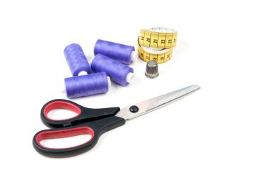 Dikiş malzemeleri ve araçları, orta dikiş konu, sarı ölçüm bandı siyah numaraları, büyük makas ve beyaz zemin üzerine metal yüksük mor