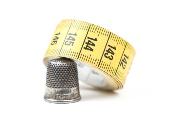 Sarı beyaz bir arka plan kasette ölçme ile metal gümüş dikiş yüksük. Dikiş aksesuarları ve araçları.