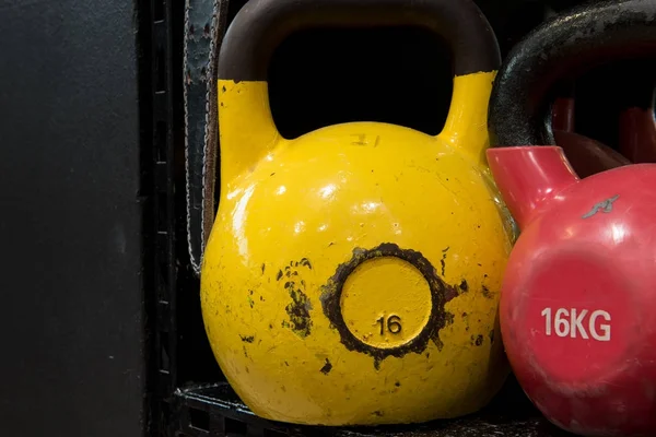 Kırmızı ve sarı bir spor salonunda bir siyah metal raf kettlebells yıpranmış