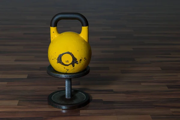 大黄色的壶在木地板上的黑色哑铃上 健身器材 — 图库照片